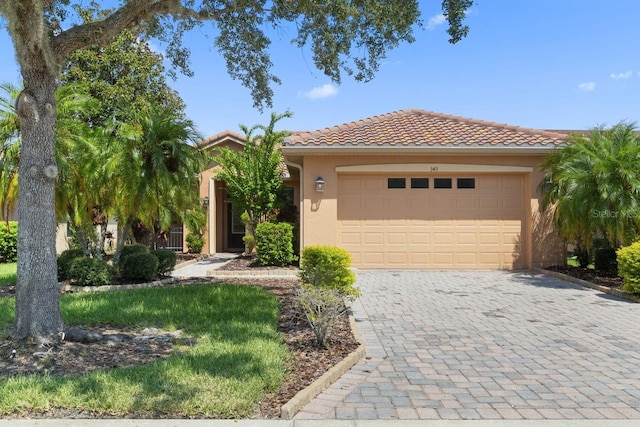 view of front facade featuring a garage, a tile roof, decorative driveway, and stucco siding