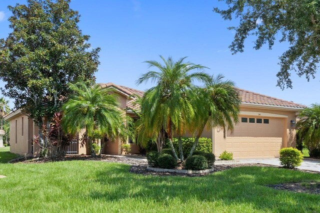 view of front of house featuring concrete driveway, a front lawn, an attached garage, and stucco siding