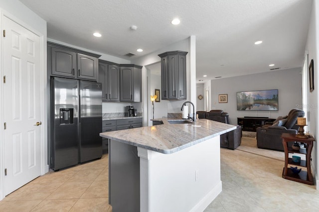 kitchen with a sink, visible vents, open floor plan, stainless steel refrigerator with ice dispenser, and gray cabinets