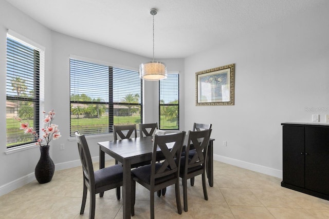 dining room with a textured ceiling, baseboards, and light tile patterned floors