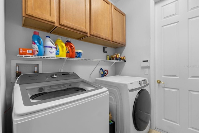 washroom with washing machine and clothes dryer and cabinet space