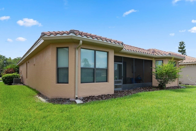 back of property with a yard, a sunroom, and stucco siding