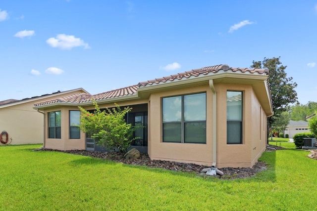 back of house with a yard, a tiled roof, and stucco siding