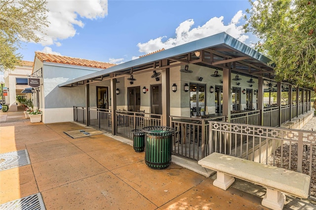 view of side of property with a tile roof, ceiling fan, and stucco siding