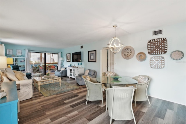 dining area with dark hardwood / wood-style flooring and an inviting chandelier