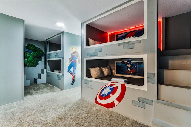 playroom featuring carpet flooring, a textured ceiling, and built in shelves