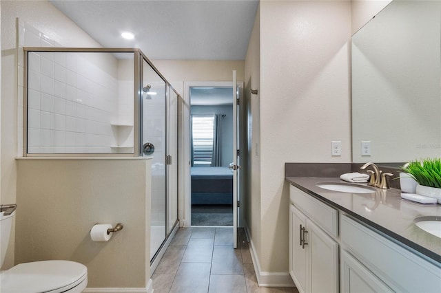 bathroom with toilet, double sink vanity, an enclosed shower, and tile patterned flooring