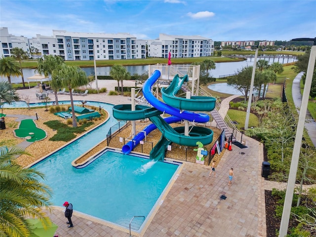 view of swimming pool featuring a patio, a water slide, and a water view