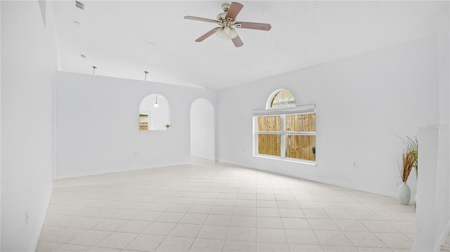 spare room with ceiling fan, lofted ceiling, and light tile patterned floors