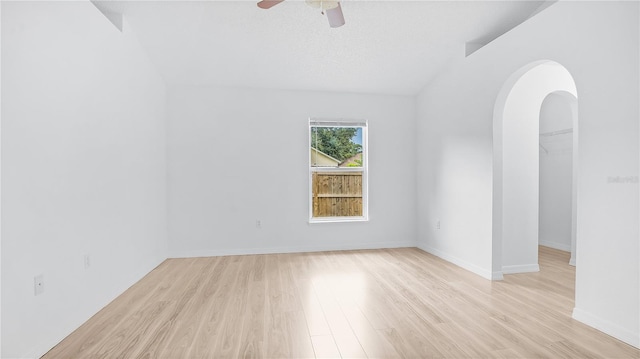 empty room with ceiling fan, light hardwood / wood-style flooring, and lofted ceiling