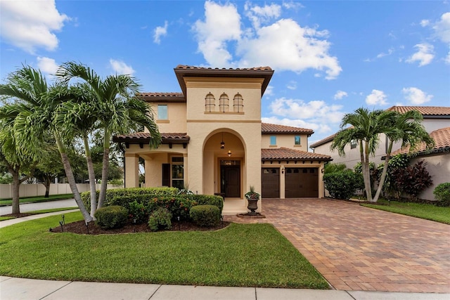 mediterranean / spanish home with a garage, a front yard, decorative driveway, and stucco siding