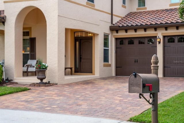 exterior space featuring a garage, a tiled roof, decorative driveway, a porch, and stucco siding