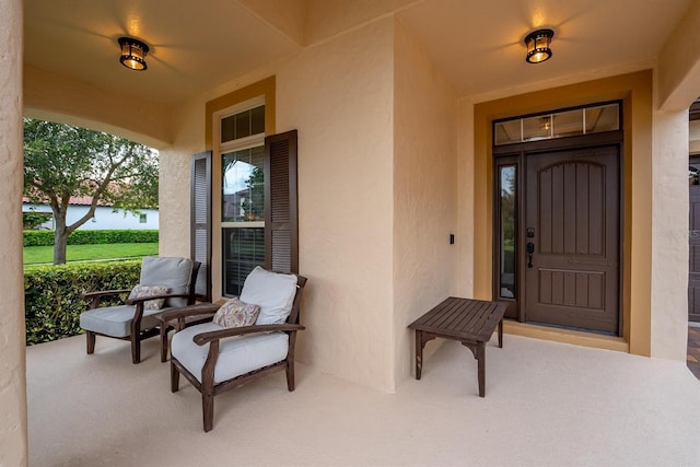 view of exterior entry with covered porch and stucco siding