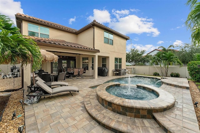 rear view of house with a fenced backyard, a tile roof, outdoor dining area, a patio area, and stucco siding