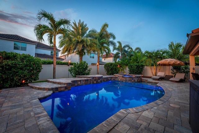 view of pool featuring a patio area, a fenced backyard, and a pool with connected hot tub