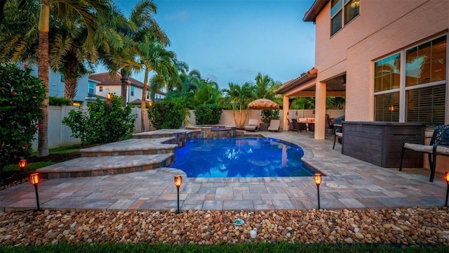 view of swimming pool with outdoor dry bar, a patio area, a pool with connected hot tub, and a fenced backyard