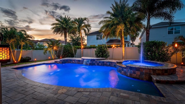 pool at dusk featuring pool water feature