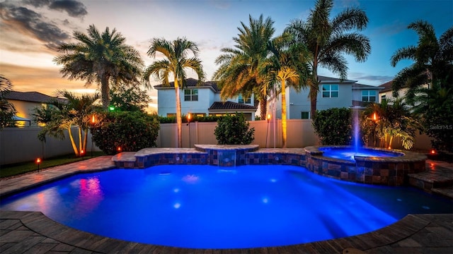 pool at dusk featuring pool water feature