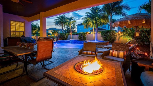 patio terrace at dusk featuring an outdoor fire pit and pool water feature