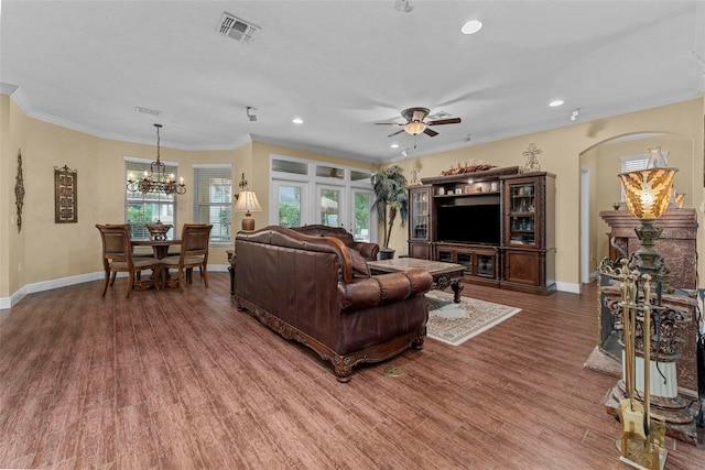 living room featuring ceiling fan with notable chandelier, crown molding, and wood-type flooring