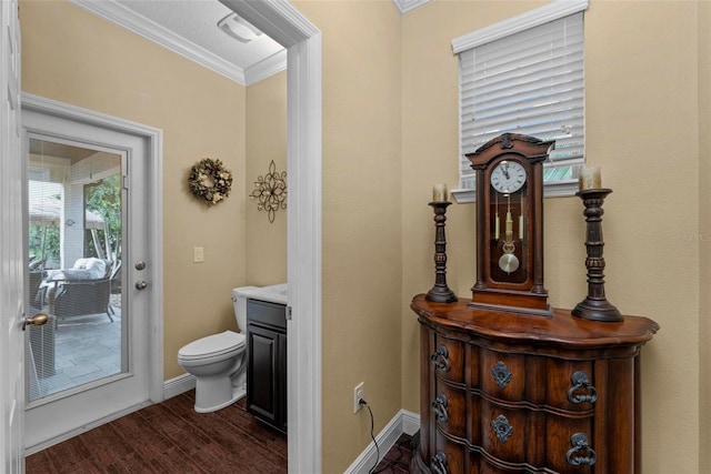 half bathroom featuring baseboards, toilet, wood finished floors, crown molding, and vanity