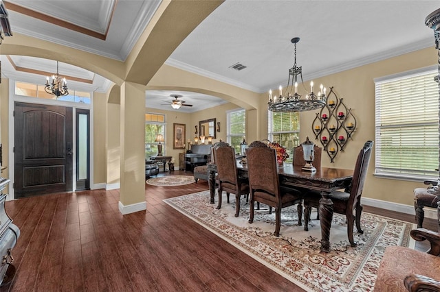 dining area with dark hardwood / wood-style flooring, crown molding, ceiling fan with notable chandelier, and a raised ceiling