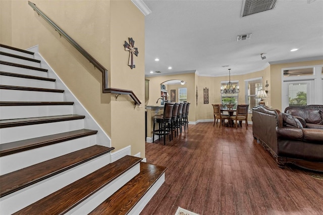 living room featuring crown molding, visible vents, dark wood finished floors, and stairs