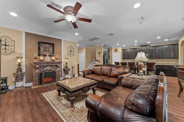 living room with dark wood-style floors, ornamental molding, and a fireplace