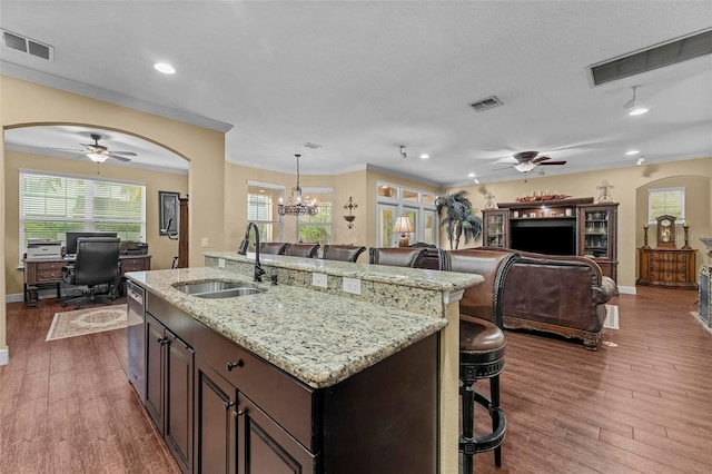 kitchen with arched walkways, open floor plan, visible vents, and a sink