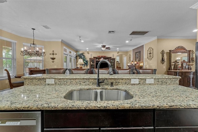 kitchen with hanging light fixtures, ceiling fan with notable chandelier, ornamental molding, light stone countertops, and sink