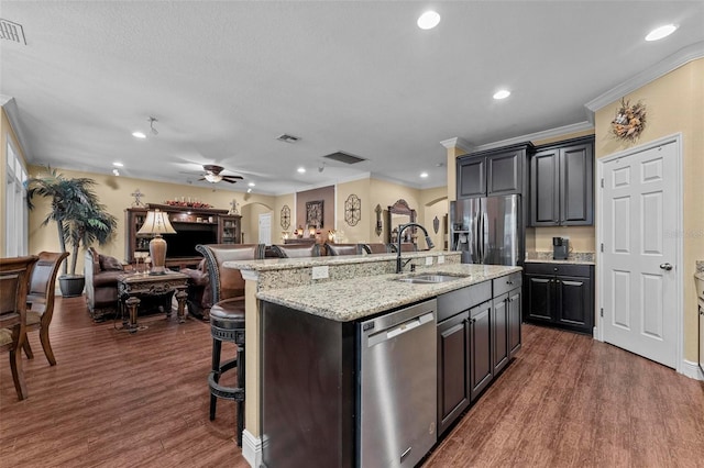 kitchen featuring dark wood-style flooring, stainless steel appliances, open floor plan, a sink, and a kitchen breakfast bar