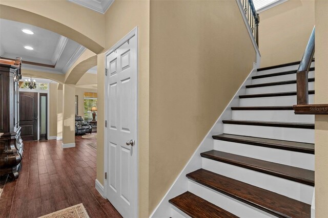 staircase with hardwood / wood-style floors and crown molding