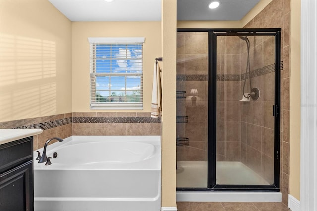 full bathroom featuring a stall shower, a garden tub, vanity, and tile patterned floors