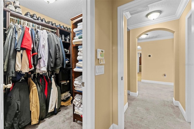 walk in closet featuring carpet floors, arched walkways, and visible vents