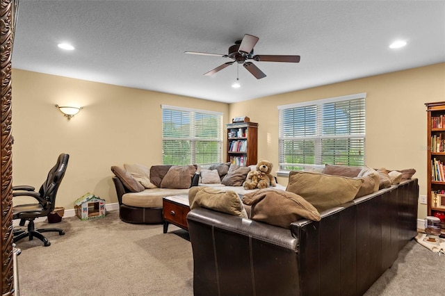 living room featuring ceiling fan, a wealth of natural light, a textured ceiling, and light carpet