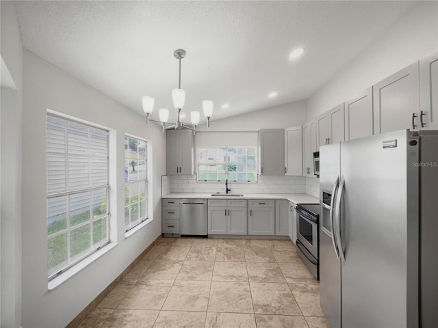 kitchen with decorative light fixtures, sink, gray cabinetry, backsplash, and stainless steel appliances