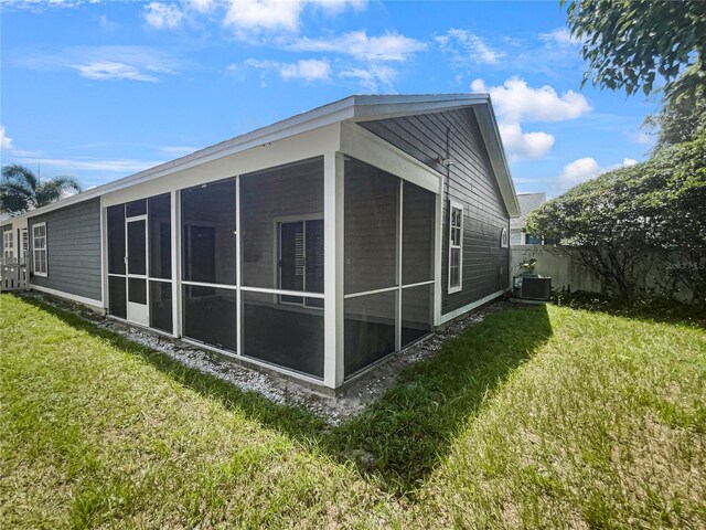 rear view of house with a sunroom, central AC, and a yard