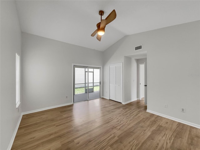 spare room with hardwood / wood-style flooring, high vaulted ceiling, and ceiling fan