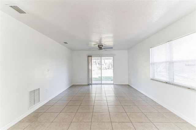 spare room with ceiling fan, a textured ceiling, and light tile patterned floors