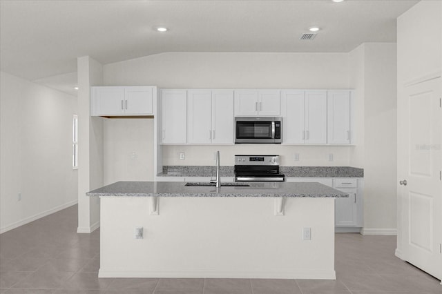 kitchen featuring appliances with stainless steel finishes, white cabinetry, a kitchen island with sink, and vaulted ceiling