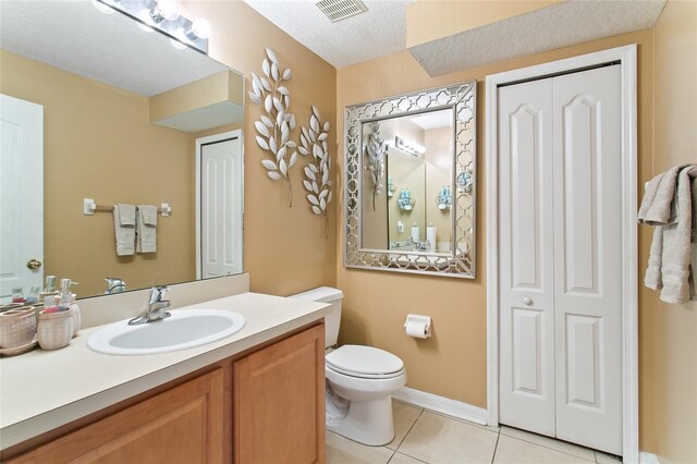 bathroom featuring tile patterned flooring, a textured ceiling, vanity, and toilet