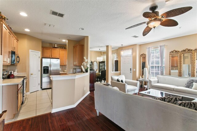 living room with ceiling fan, light hardwood / wood-style flooring, and a textured ceiling