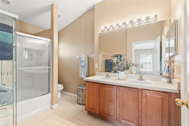 full bathroom with tile patterned floors, toilet, dual vanity, and enclosed tub / shower combo