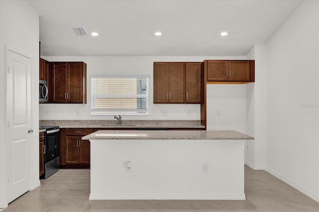 kitchen featuring stainless steel appliances, sink, light tile patterned flooring, and a kitchen island