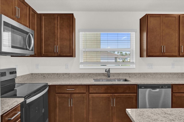 kitchen featuring stainless steel appliances, light stone countertops, sink, and a wealth of natural light