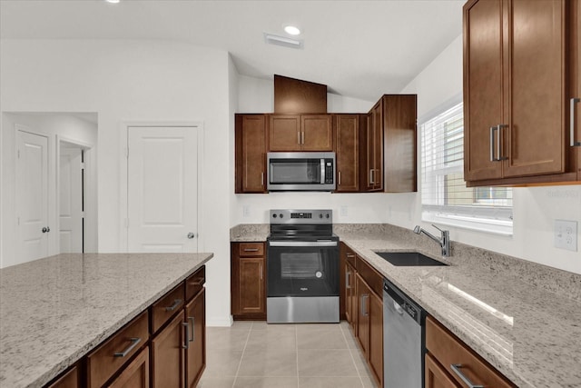 kitchen with stainless steel appliances, sink, light stone countertops, vaulted ceiling, and light tile patterned floors