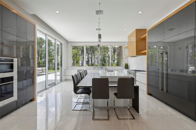 kitchen featuring sink, decorative light fixtures, light tile patterned floors, a breakfast bar area, and stainless steel appliances