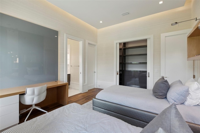 bedroom with hardwood / wood-style floors, built in desk, and a closet