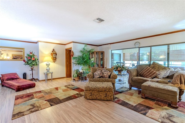 living room with ornamental molding, light hardwood / wood-style flooring, and a textured ceiling