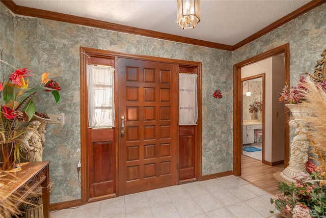 entrance foyer with light hardwood / wood-style floors, a textured ceiling, and crown molding